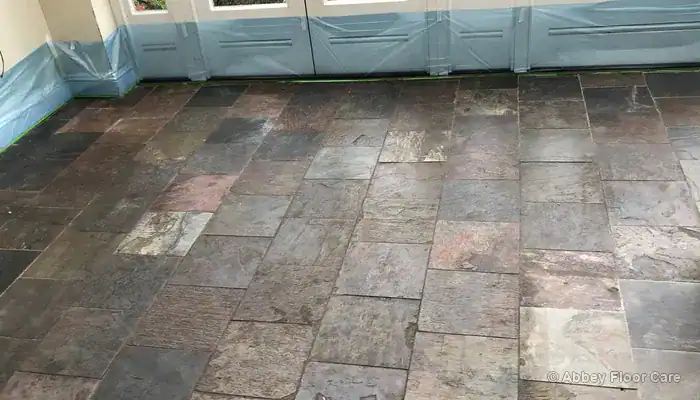 Worn slate floor with dull patches and pale traffic lanes